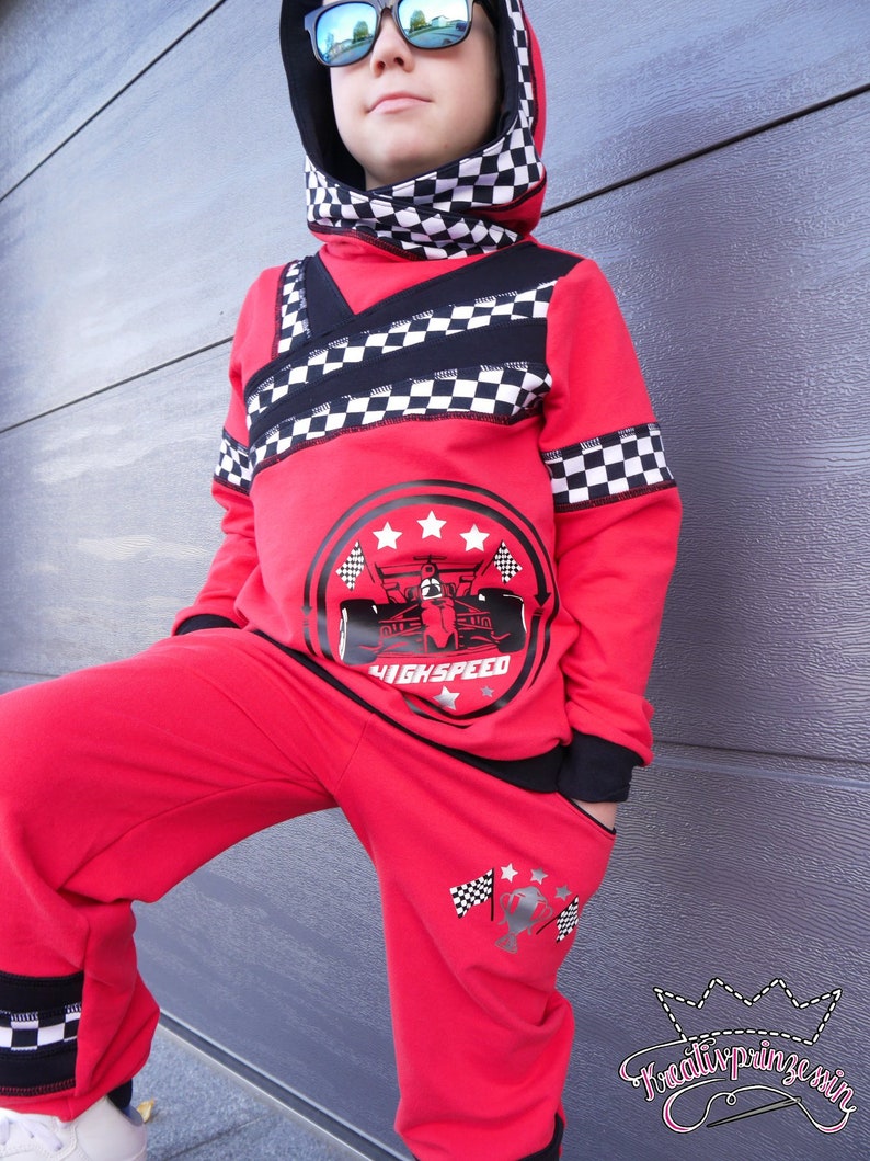 May include: Red hooded sweatshirt and matching sweatpants with black and white checkered accents. The sweatshirt features a black and white graphic of a race car with the text "High Speed". The sweatpants have a black and white graphic of a checkered flag and stars on the left leg.