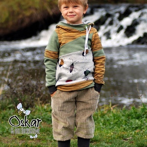May include: A young boy wearing a green, yellow, and white striped hoodie with a bug print. The hoodie has a zipper and a drawstring. The boy is also wearing brown corduroy pants.
