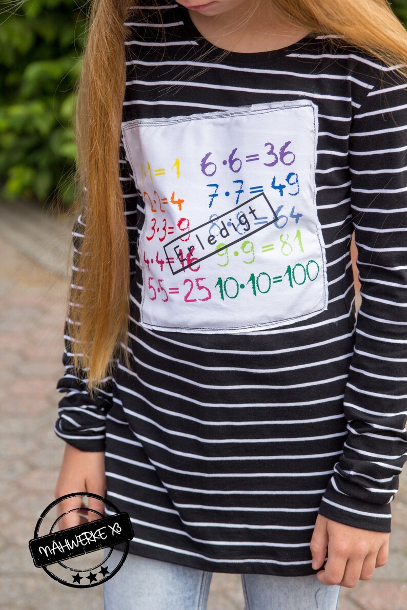 May include: A black and white striped long-sleeved shirt with a white patch on the front. The patch has colorful handwritten math equations, including "1x1=1", "6x6=36", "7x7=49", "3x3=9", "4x4=16", "5x5=25", "9x9=81", and "10x10=100". The patch also has a red rectangle with the word "Erledigt" written in it.