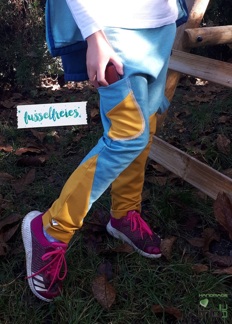 Puede incluir: Un par de leggings azules y amarillas con un bolsillo en el lateral. Las leggings est&aacute;n hechas de una tela suave y c&oacute;moda y tienen un ajuste holgado. El texto "fusselfreies" es visible en una etiqueta blanca.