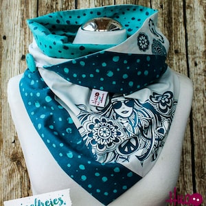 May include: A white, teal, and turquoise patterned scarf with a peace sign and a woman's face design. The scarf is folded and displayed on a white mannequin. The text "fussselfreies" is visible in the lower left corner of the image.