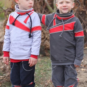 May include: Two young boys wearing gray and white long-sleeved shirts with red and gray trim. The shirts have a unique design with a diagonal red stripe across the front. The boys are wearing blue corduroy pants with red trim.