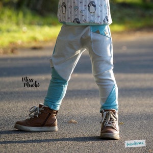 Puede incluir: Un ni&ntilde;o lleva pantalones de chevron azul y blanco con ribete turquesa. Los pantalones tienen un bolsillo de parche en la pierna derecha. El ni&ntilde;o lleva zapatillas altas marrones.