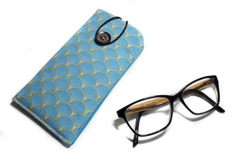 May include: A blue and gold patterned glasses case with a button closure and a pair of black framed glasses with a wooden temple.