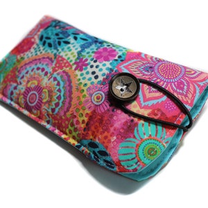 May include: A colorful floral patterned glasses case with a turquoise blue border and a star-shaped button closure.