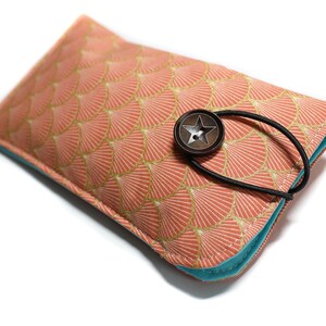 May include: A pink and gold patterned fabric glasses case with a turquoise lining and a star-shaped button closure.