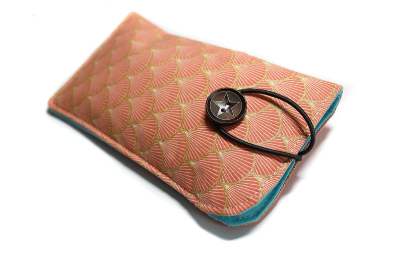 May include: A pink and gold patterned fabric glasses case with a turquoise lining and a star-shaped button closure.