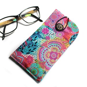 May include: A colorful floral patterned glasses case with a button closure. The case is made of fabric and has a bright pink, blue, and green design.