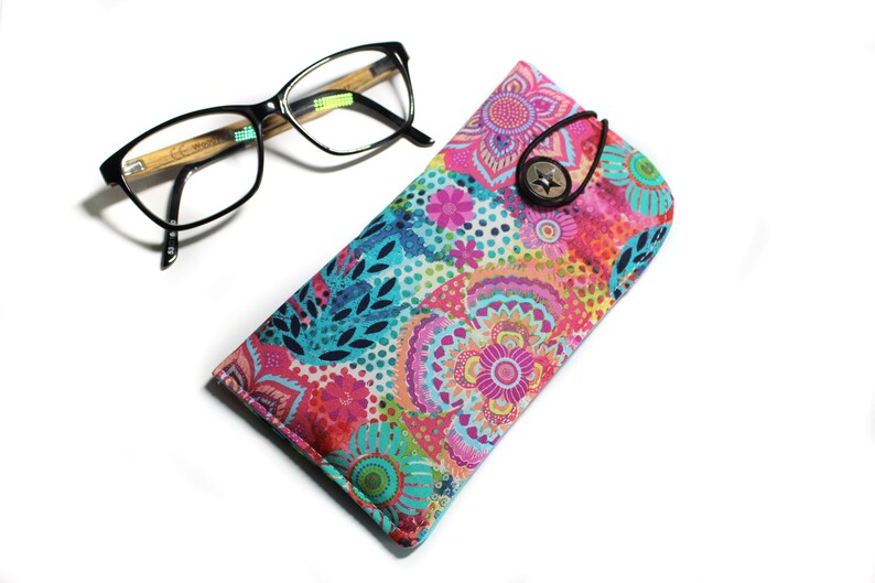 May include: A colorful floral patterned glasses case with a button closure. The case is made of fabric and has a bright pink, blue, and green design.
