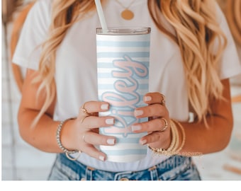 May include: A white stainless steel tumbler with a blue and white striped design and the name "Riley" written in pink on the side.