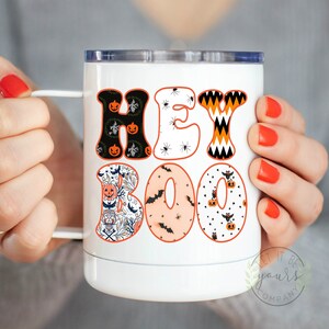 May include: White stainless steel tumbler with a black and orange "Hey Boo" design featuring pumpkins, bats, and spiders.