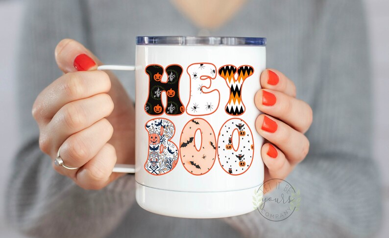 May include: White stainless steel tumbler with a black and orange "Hey Boo" design featuring pumpkins, bats, and spiders.