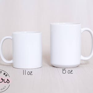 May include: Two white ceramic mugs, one 11 oz and one 15 oz, on a light wood surface. The mugs are blank and ready for personalization.