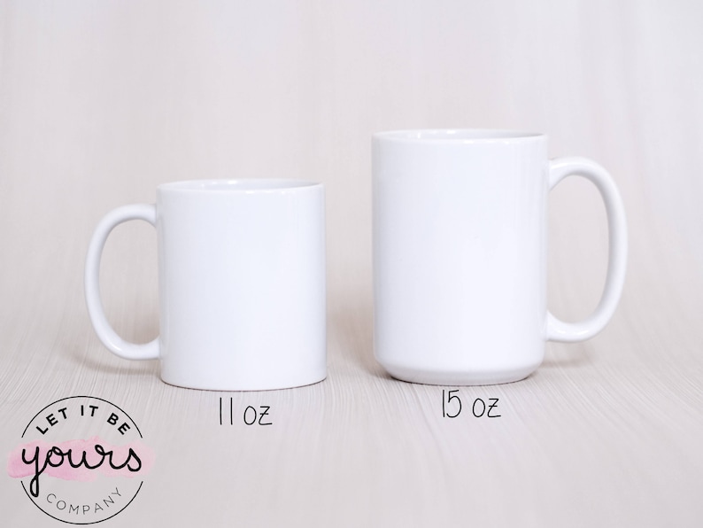 May include: Two white ceramic mugs, one 11 oz and one 15 oz, on a light wood surface. The mugs are blank and ready for personalization.