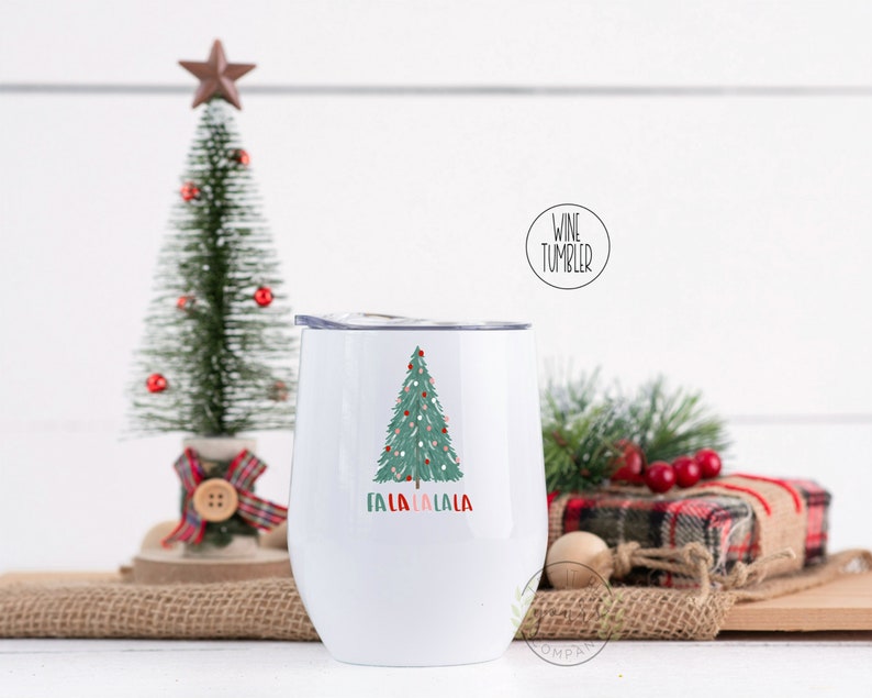 May include: White stainless steel wine tumbler with a green Christmas tree design and the text "Fa la la la la" in red, pink, and green.