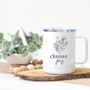 May include: White stainless steel travel mug with a black floral design and the text "choose joy".