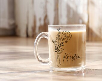 May include: A clear glass mug with a black floral design and the name "Kristen" printed on the side. The mug is filled with a light brown beverage.