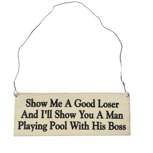 May include: A white wooden sign with black text that reads "Show Me A Good Loser And I'll Show You A Man Playing Pool With His Boss".