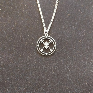 May include: A silver necklace with a circular pendant featuring a stylised design of crossed swords and a shield.