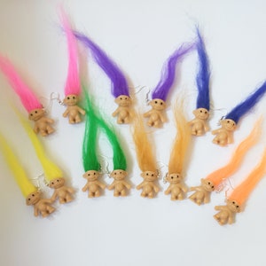 May include: A set of 10 pairs of troll doll earrings. Each pair features a small troll doll with colourful hair. The hair colours include pink, purple, green, yellow, orange, and blue.