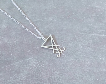 May include: A silver necklace with a pendant featuring a triangle with a stylized design inside. The pendant is on a silver chain.