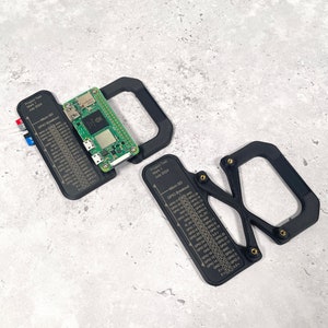 Puede incluir: Un marco de plástico negro con una placa de circuito verde en su interior. El marco tiene una etiqueta que dice "Project Test Mark 1 July 2024" y un diagrama de una tarjeta micro SD y un breakout GPIO.