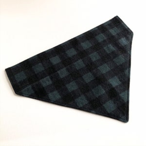 May include: A black and green plaid bandana for a pet. The bandana is made of a soft, fuzzy fabric.