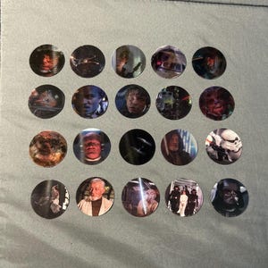 May include: A collection of twenty circular stickers featuring various Star Wars characters and scenes, including portraits of Luke Skywalker, Obi-Wan Kenobi, Darth Vader, Chewbacca, and Stormtroopers, arranged in a four-by-five grid pattern.