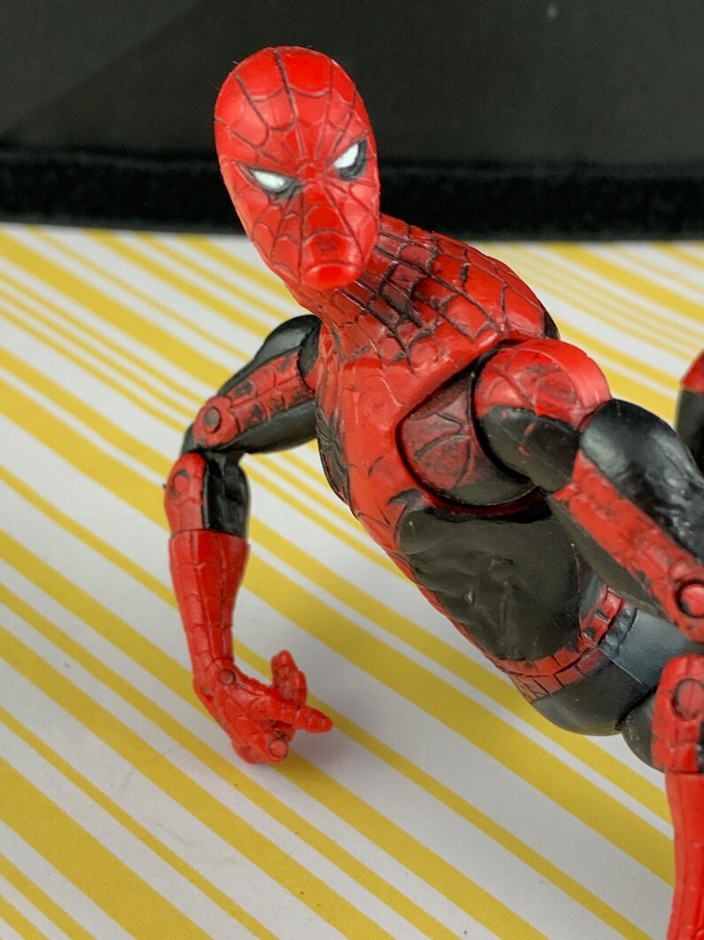 K&ouml;nnte beinhalten: Eine rot-schwarze Spider-Man-Actionfigur. Die Figur hat ein detailliertes Design mit roter Maske und Anzug, schwarzen Akzenten und beweglichen Gelenken. Die Figur ist mit einem ausgestreckten Arm posiert.