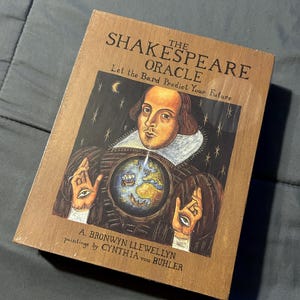以下が含まれることがあります： 「The Shakespeare Oracle: Let the Bard Predict Your Future」というタイトルの長方形のボックスセット。表紙には、A. ブロンウィン・ルウェリンとシンシア・フォン・ビューラーによる、地球儀、星、手のひらに描かれた目を持つウィリアム・シェイクスピアのイラストが描かれています。