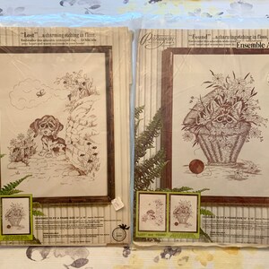May include: Two needlepoint embroidery kits featuring a brown and white puppy and a raccoon in a basket of flowers. The kits are packaged in brown paper with a white border and the text "Lost" and "Found" on the front. The kits are designed to fit a frame size of 12 x 16 inches.