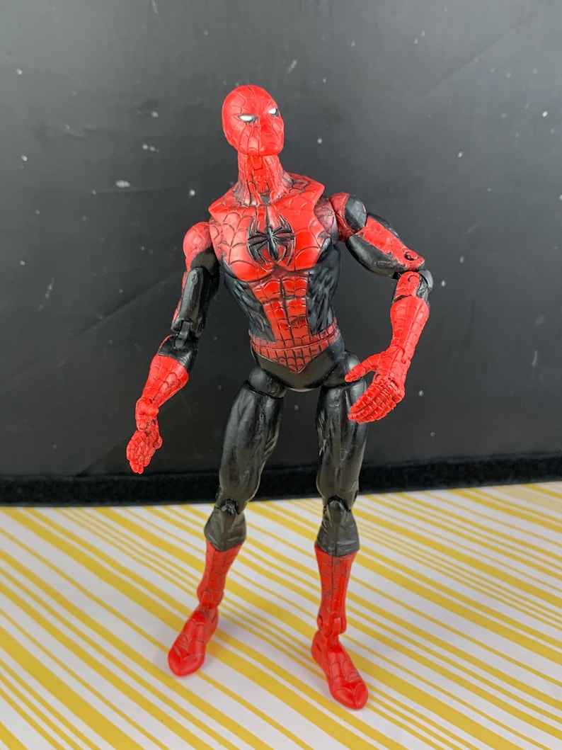 K&ouml;nnte beinhalten: Eine Spider-Man-Actionfigur in dynamischer Pose. Die Figur hat ein rot-schwarzes Farbschema mit einem detaillierten Netzmuster auf Brust und Maske. Die Pose deutet auf Action hin, mit beweglichen Gelenken und detailliertem Design.