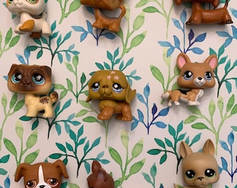 May include: A collection of nine small plastic toy dogs in various breeds and colors. The dogs are all standing on a white background with a green and blue floral pattern.
