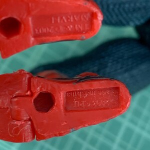 May include: Close-up of two red plastic toy feet. The feet have a hole in the center and the text "TM & &copy; 2003 MARVEL" is visible on one foot. The other foot has the text "Made in China".