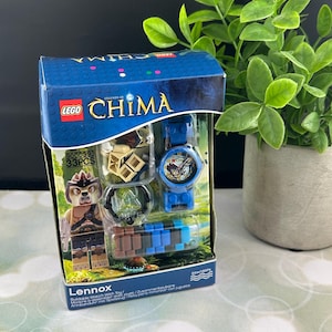May include: A LEGO Legends of Chima Lennox buildable watch toy set. The box is blue with the LEGO and Chima logos. The set includes a blue watch, a minifigure, and other accessories. The watch is water resistant to 50m.