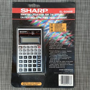 May include: A Sharp EL-509SB scientific calculator in its original black packaging. The device features a white keypad with black buttons, a digital display, and text detailing 72 functions. The packaging includes a barcode and specifications.