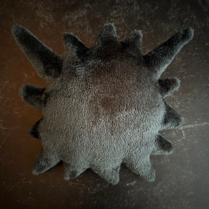 Peut inclure: Un jouet en peluche noir et piquant avec une texture douce et duveteuse. Le jouet a la forme d'une boule ronde avec de multiples pointes piquantes.