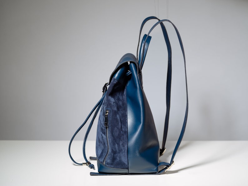 May include: A blue leather backpack with a suede flap and adjustable straps.
