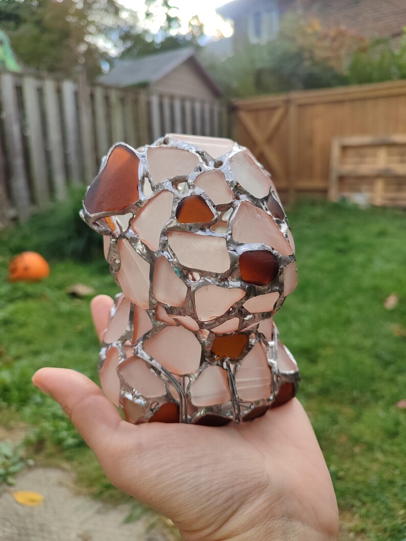 May include: A small, hand-crafted sculpture of a dog made from various pieces of glass, including clear, white, and brown glass. The glass pieces are joined together with silver-colored metal.