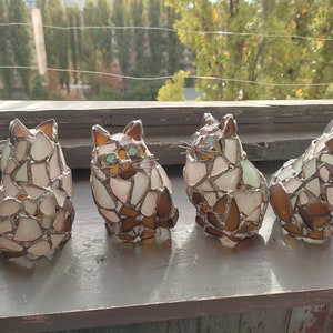 May include: Four mosaic glass cat figurines in white, brown, and green tones. The cats are arranged in a row, facing the same direction.