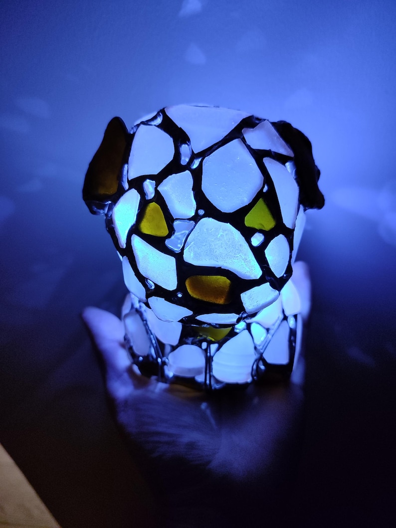 May include: A white glass sculpture of a dog, with black lines and yellow accents, illuminated from within.