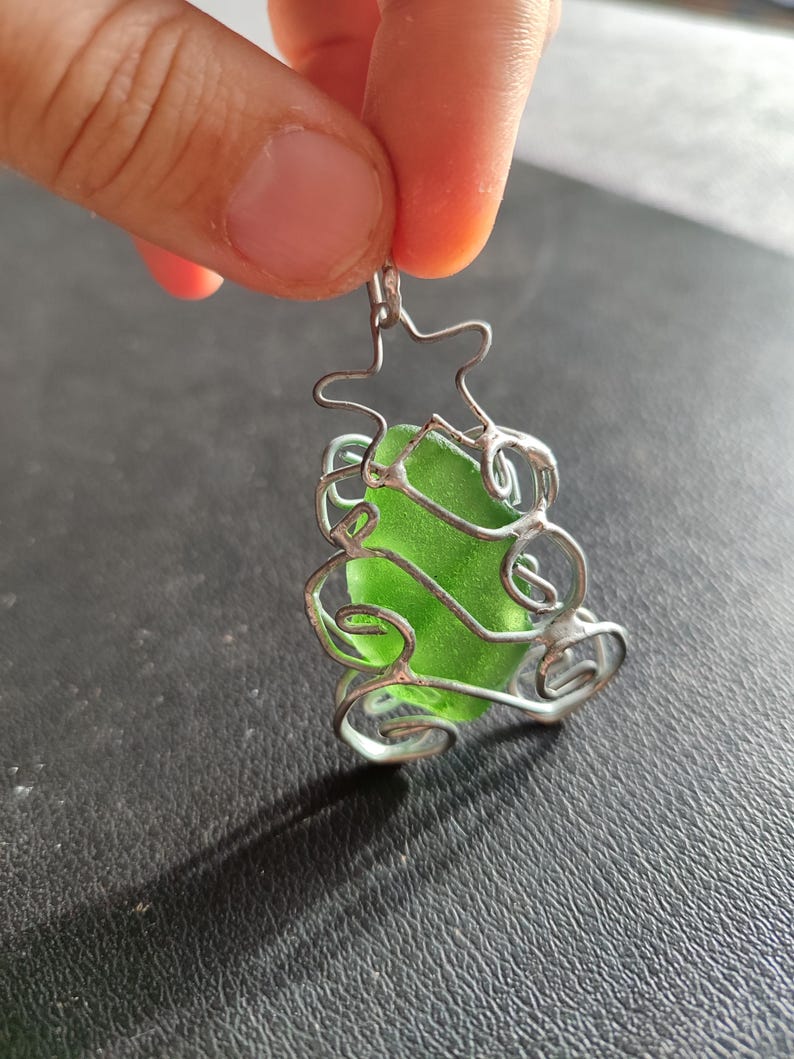 May include: A green glass sea glass charm encased in a silver wire tree design.