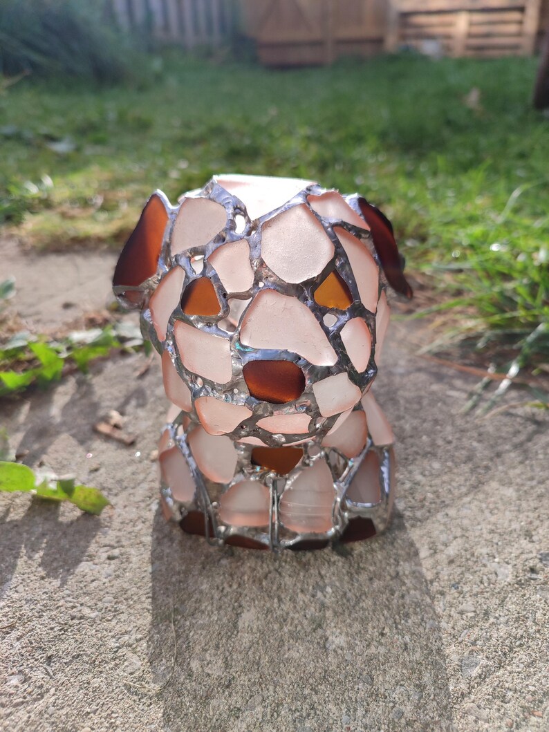 May include: A small, white, glass sculpture of a dog made from many pieces of glass. The sculpture is made in the style of stained glass, with the pieces of glass held together by silver metal.