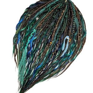 May include: A bundle of synthetic dreadlocks in shades of teal, brown, and blue. The dreads are styled with wavy and straight sections, some adorned with beads and lace. The hair is arranged against a white background.