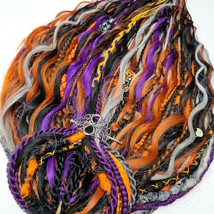 May include: A collection of colorful dreadlocks in shades of orange, black, purple, gray, and yellow. The dreadlocks are styled with a silver hair accessory. The overall theme is a Halloween or gothic aesthetic.