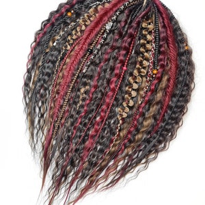 Könnte beinhalten: Ein Set synthetischer Haarverlängerungen in Schwarz, Braun und Burgunderrot mit Perlen und Kettenakzenten. Die Verlängerungen sind wellig und haben einen Boho-Stil.