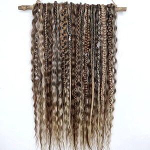 May include: A wall hanging made of brown and blonde synthetic hair braids with silver beads and charms.
