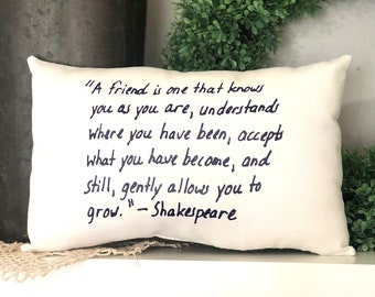 May include: White throw pillow with black handwritten text that reads "A friend is one that knows you as you are, understands where you have been, accepts what you have become, and still, gently allows you to grow. -Shakespeare"