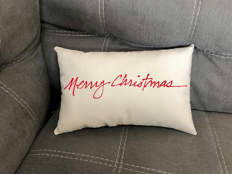 May include: White throw pillow with the words "Merry Christmas" written in red cursive script.