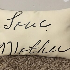 May include: A white pillow with black cursive writing that says "Love you Mother".